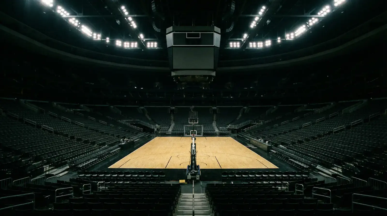 Tabela oficial de basquetebol NBA vazia e iluminada num pavilhão silencioso visto da bancada